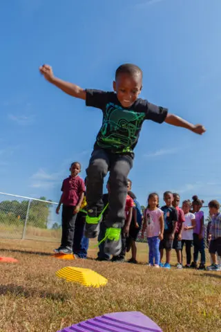 A boy leaps in the air as children watch